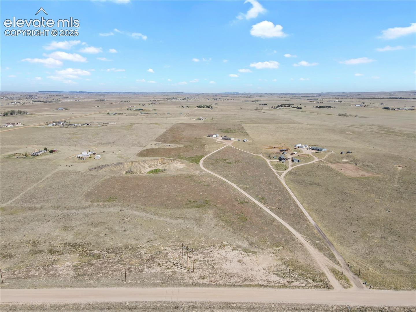 Expansive acreage featuring open terrain, gravel access roads, and utility infrastructure