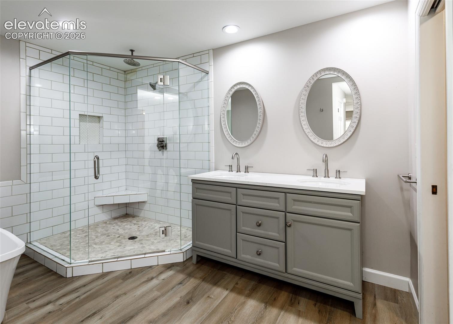 Glass-enclosed shower with white subway tile, built-in bench, and tiled floor