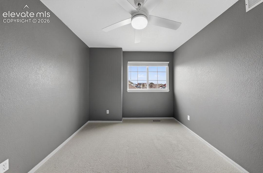 Interior room featuring neutral wall paint, wall-to-wall carpeting, and a white ceiling fan with integrated lighting