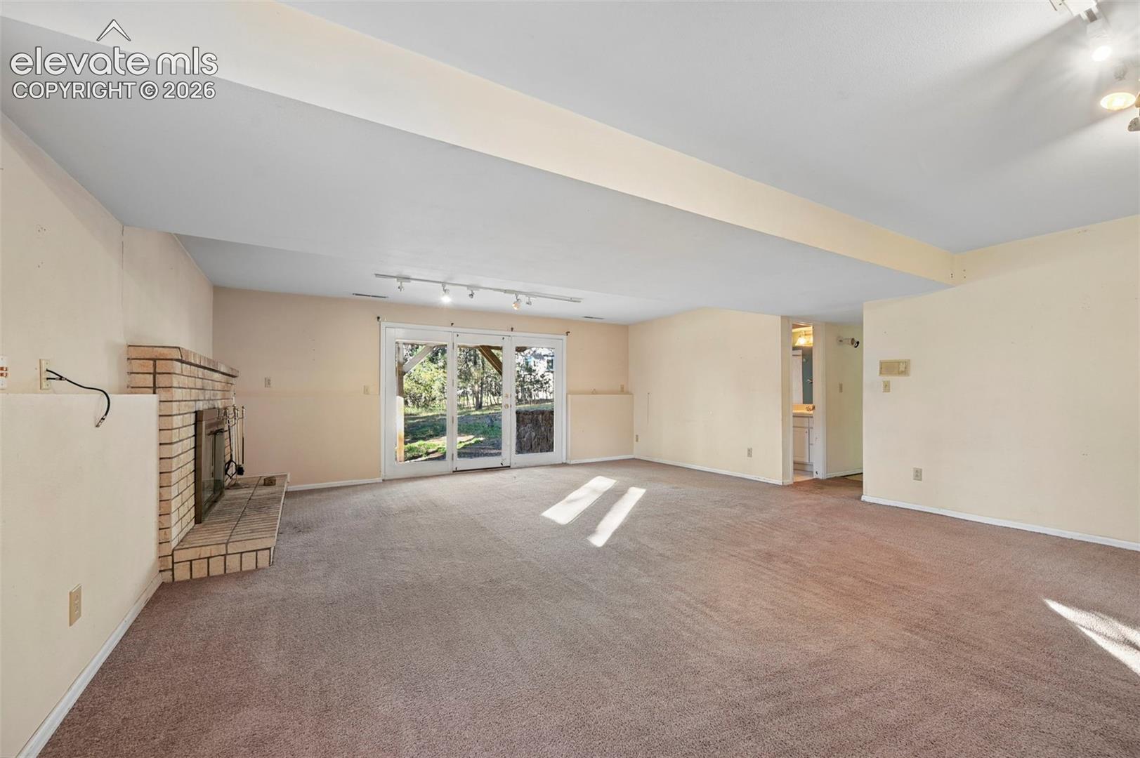 Expansive room featuring a brick fireplace, track lighting, and sliding glass doors
