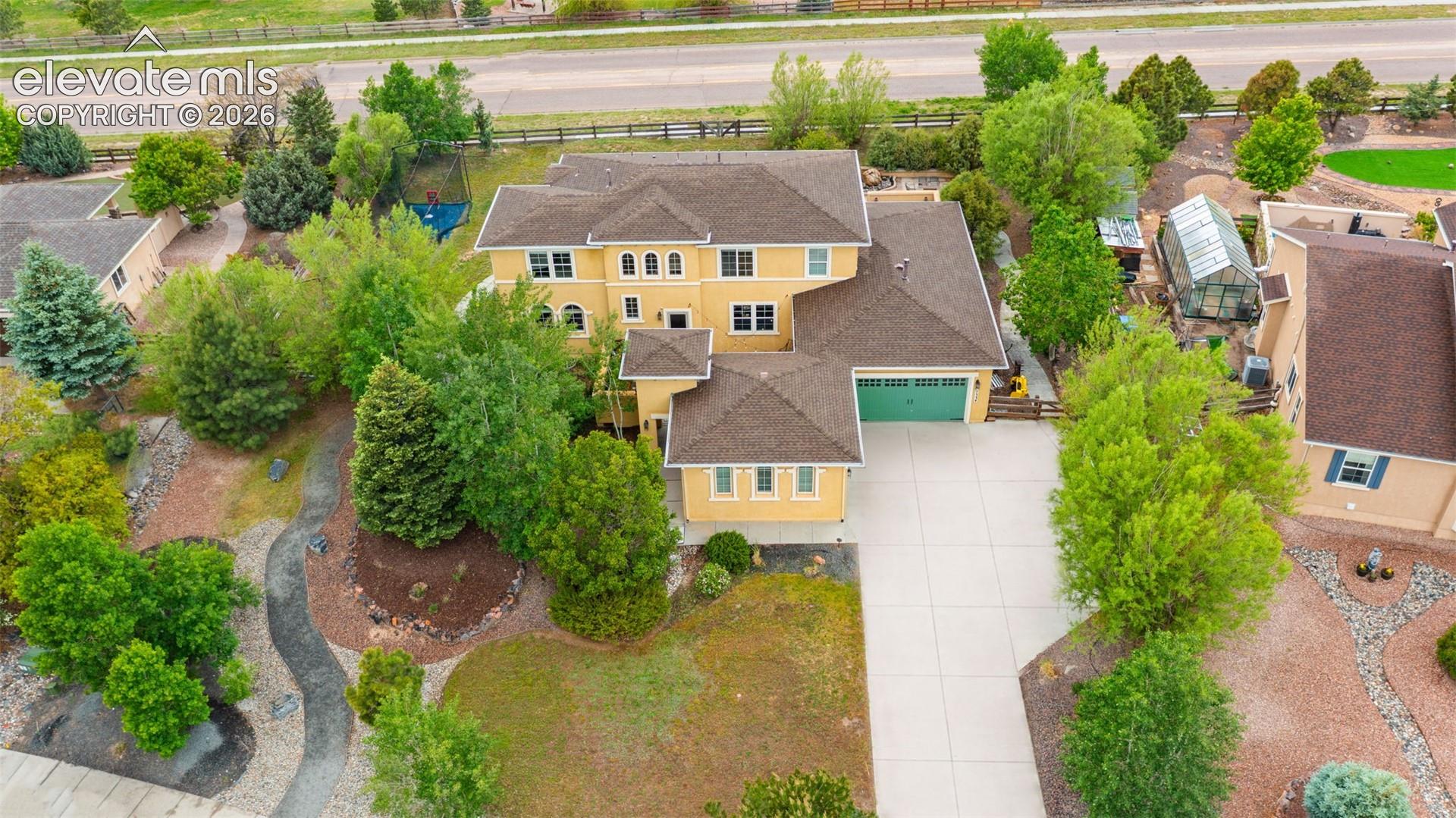 Expansive property featuring a multi-level residence with a three-car garage, mature landscaping, a private driveway, and an on-site greenhouse