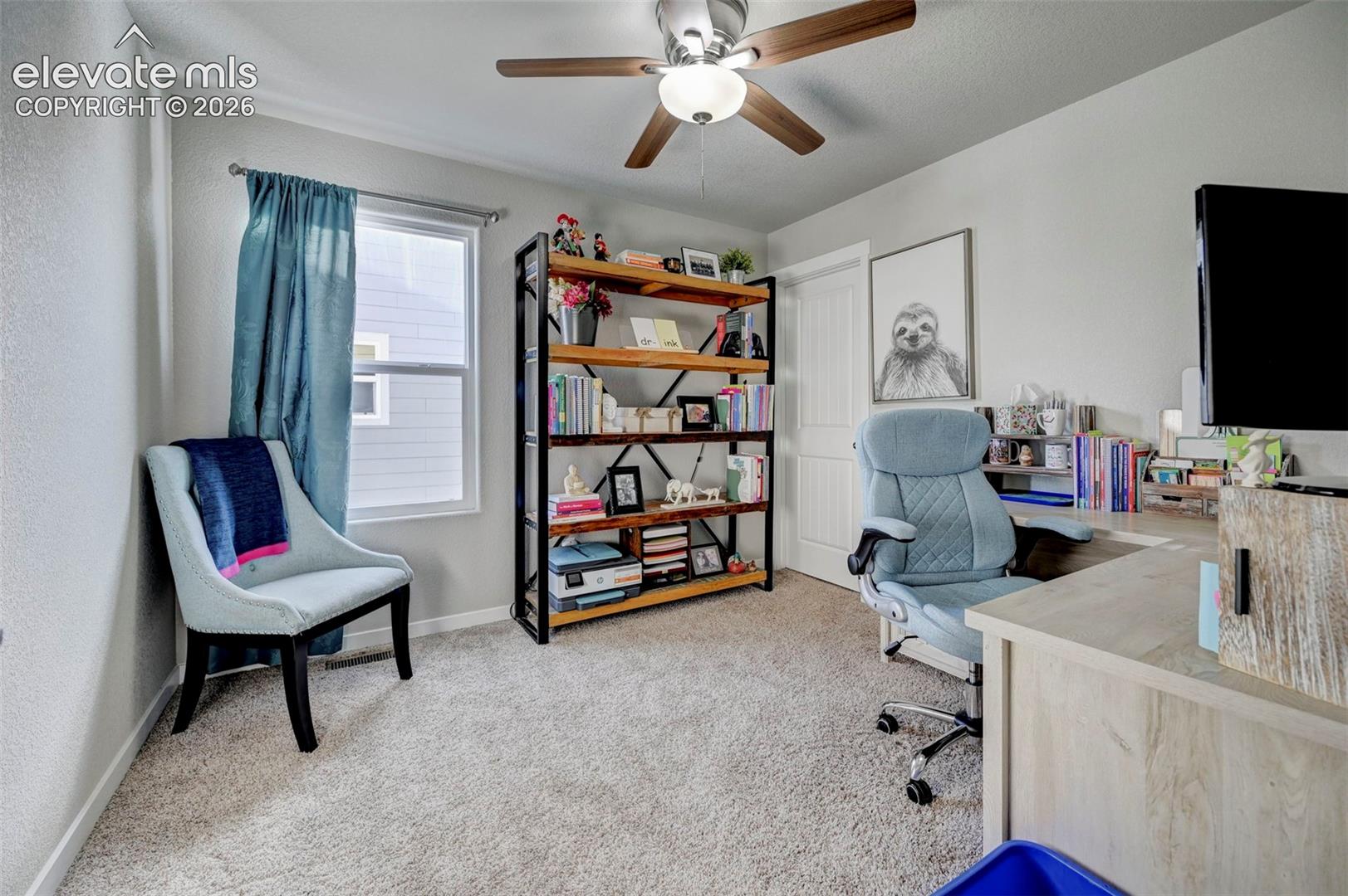 Neutral-toned room featuring plush wall-to-wall carpeting, single-pane window with a metal rod, white two-panel interior door, and a ceiling fan with integrated lighting