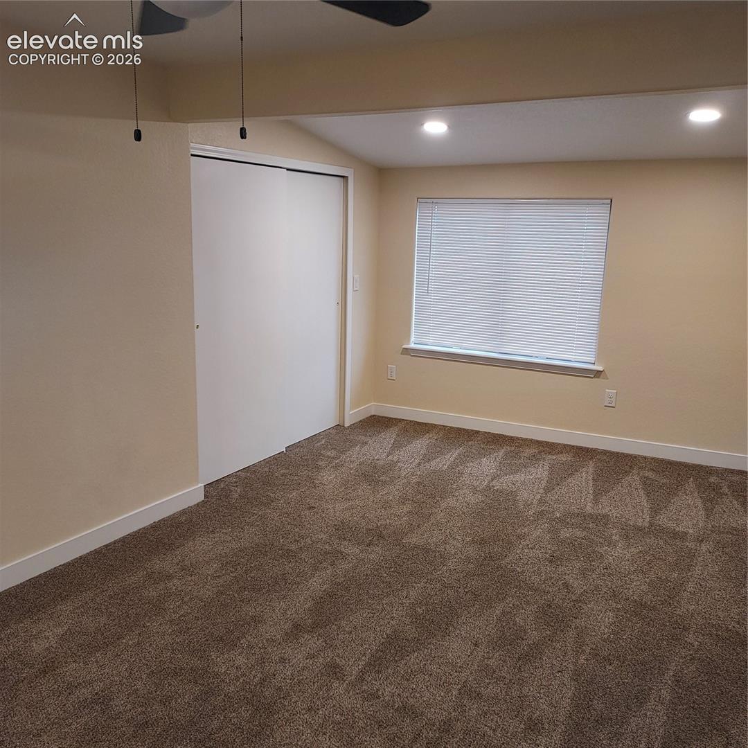 Room featuring neutral wall tones, recessed lighting, carpeted flooring, a sliding-door closet, and a window with fitted blinds