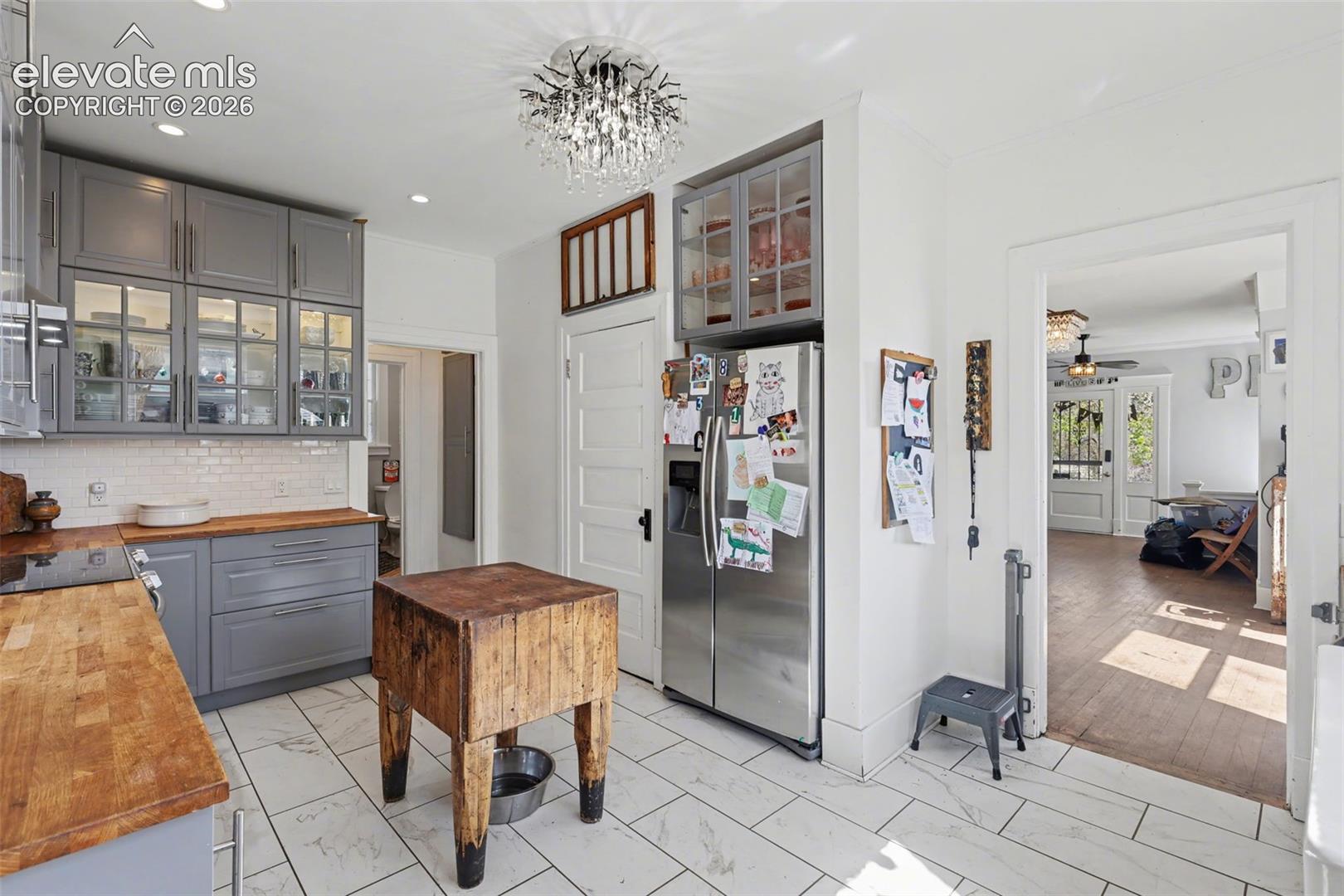 Main house kitchen featuring gray cabinets, light tile, wood counters, and recessed lighting