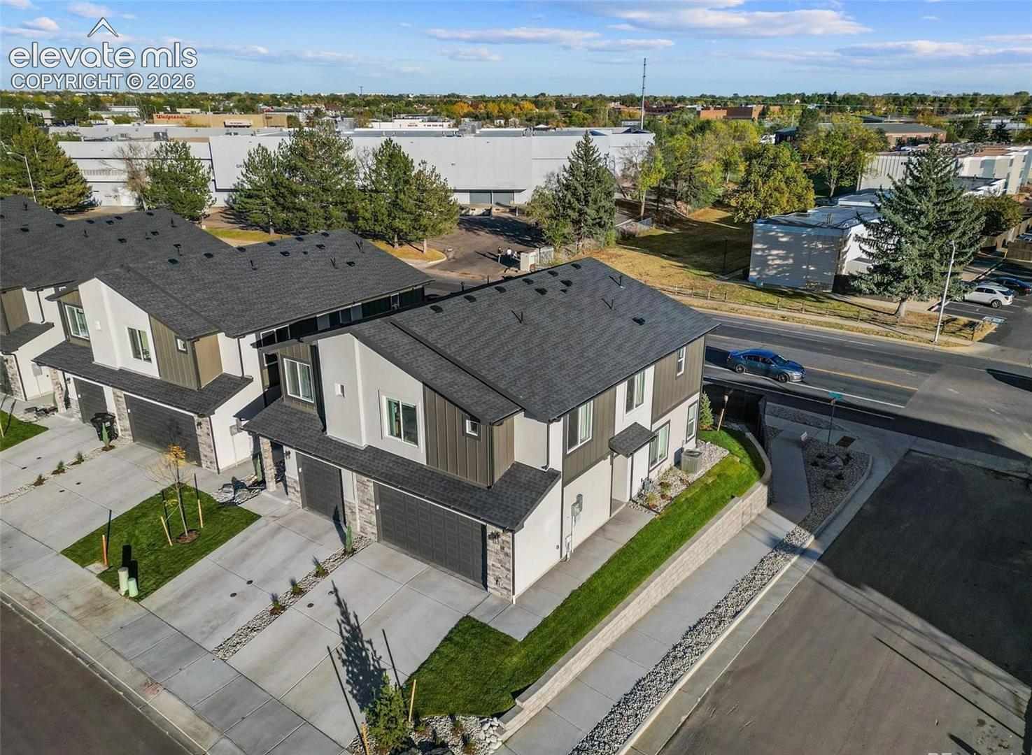 Multi-level exterior featuring a combination of stone veneer and vertical siding, attached multi-car garages, asphalt shingle roofing, and concrete driveways