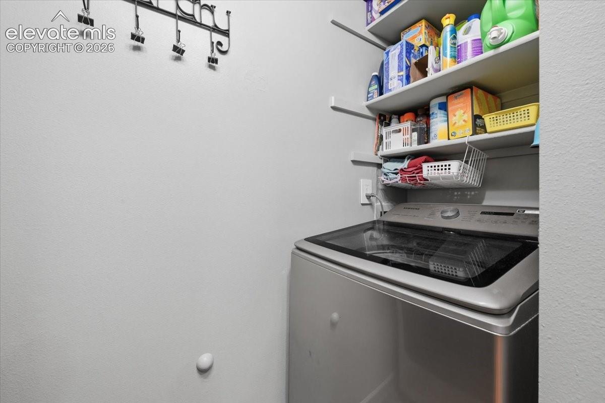 Dedicated utility space featuring built-in wooden shelving and a wall-mounted electrical outlet
