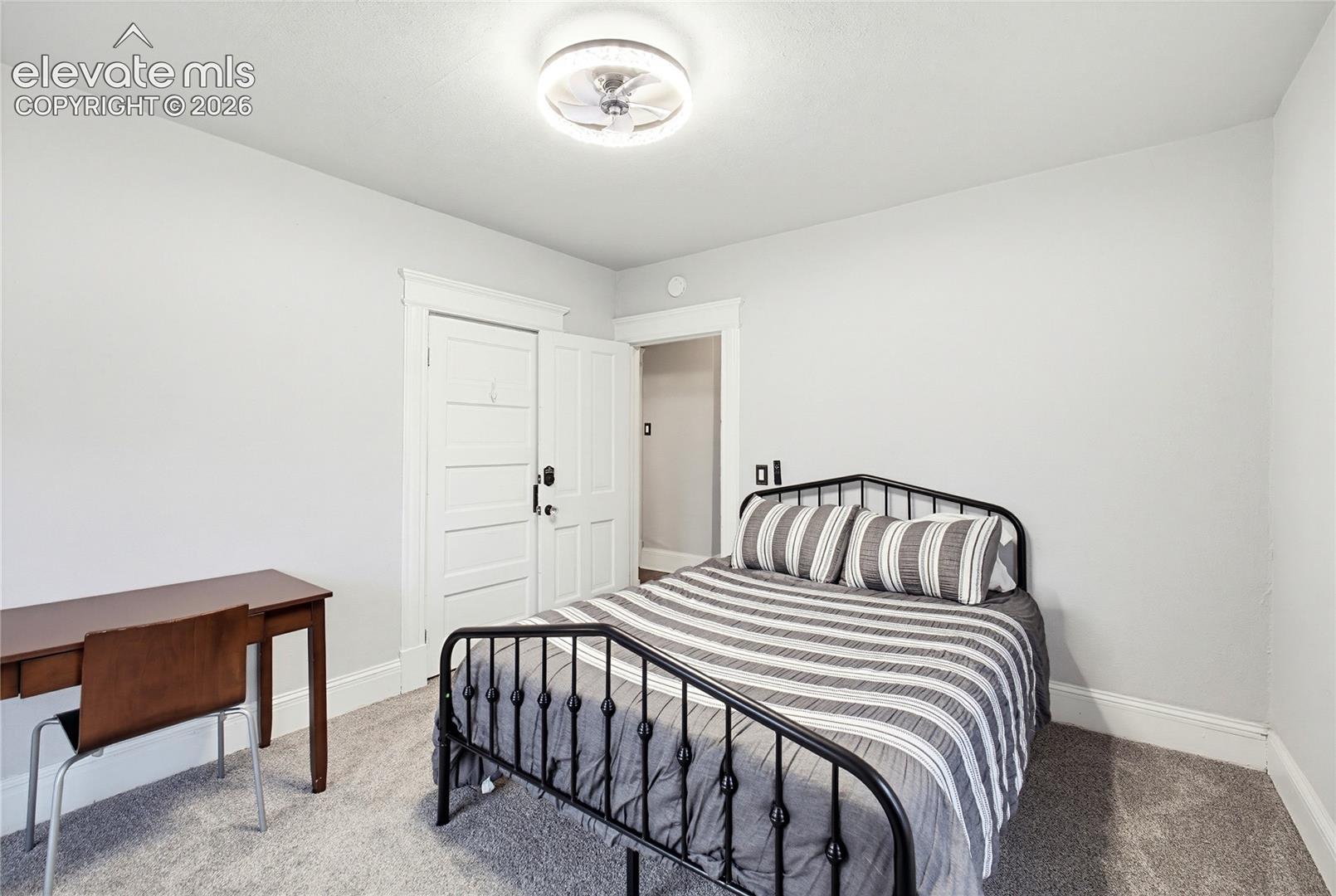 White walls, light-toned carpet, and a ceiling-mounted light fixture