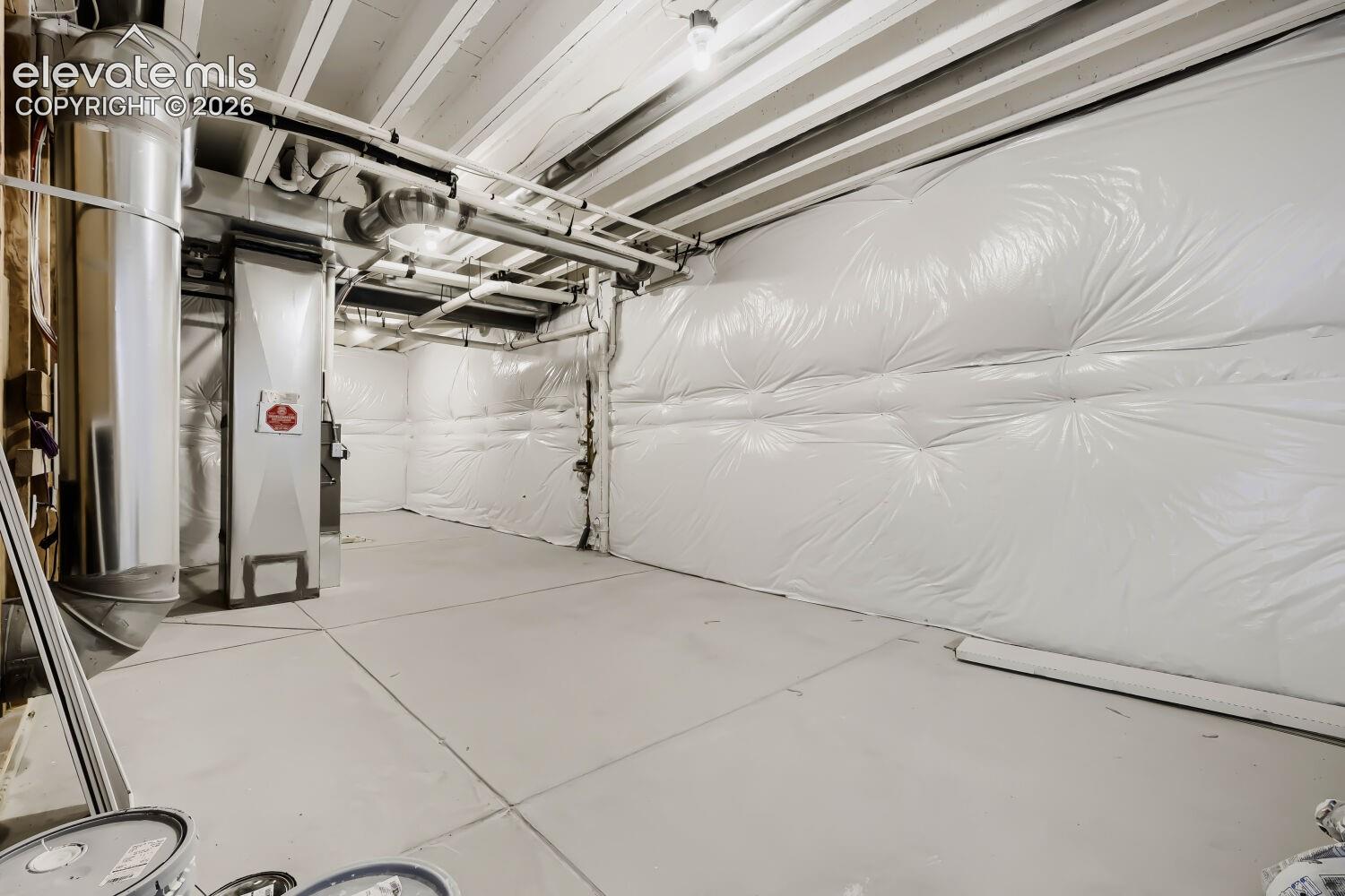 Spacious garage with epoxy-coated flooring, overhead storage systems, and integrated mechanical infrastructure including HVAC components and electrical conduit