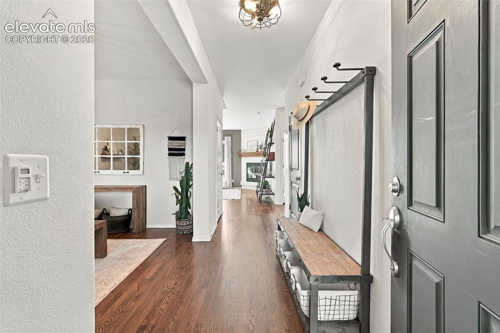 Entryway featuring wood-finish flooring, vaulted ceilings, and a recessed fireplace