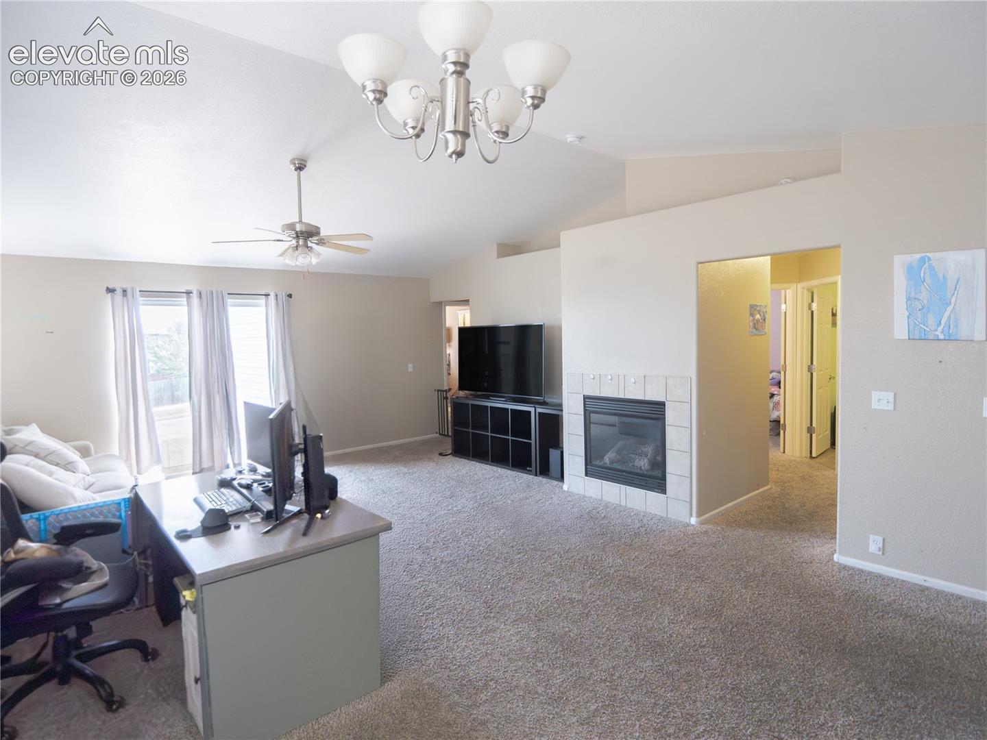 Spacious room featuring vaulted ceilings, a ceiling fan, and a chandelier