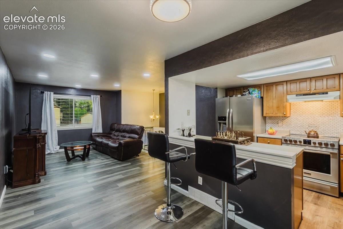 Open-concept living area featuring wood-finish flooring, recessed lighting, and a kitchen pass-through with counter seating