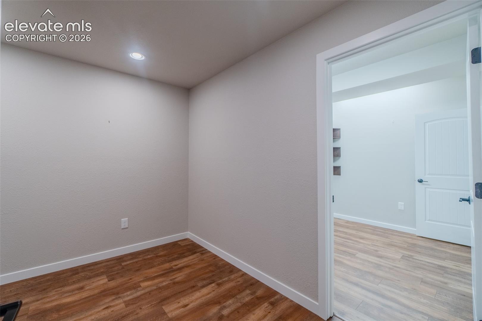 Interior room featuring wood-finish flooring, recessed lighting, and a white baseboard trim