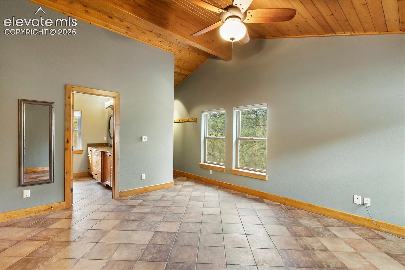 Vaulted ceiling with exposed wood planking, tile flooring, dual-pane windows, and a ceiling fan