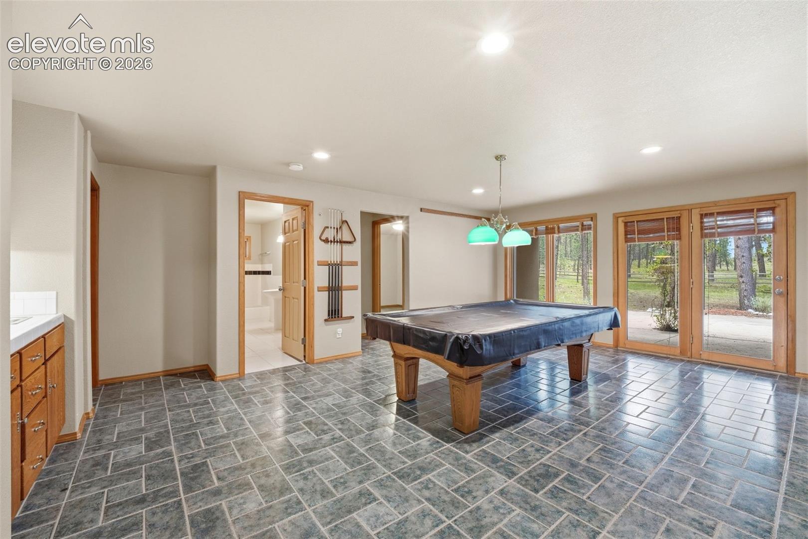Spacious room featuring patterned gray floor tile and multiple sets of French doors with wood-finish frames