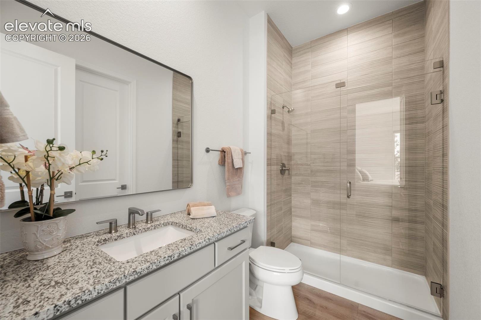 Beautiful vanity with a granite countertop, undermount sink, walk-in shower and walkin closet