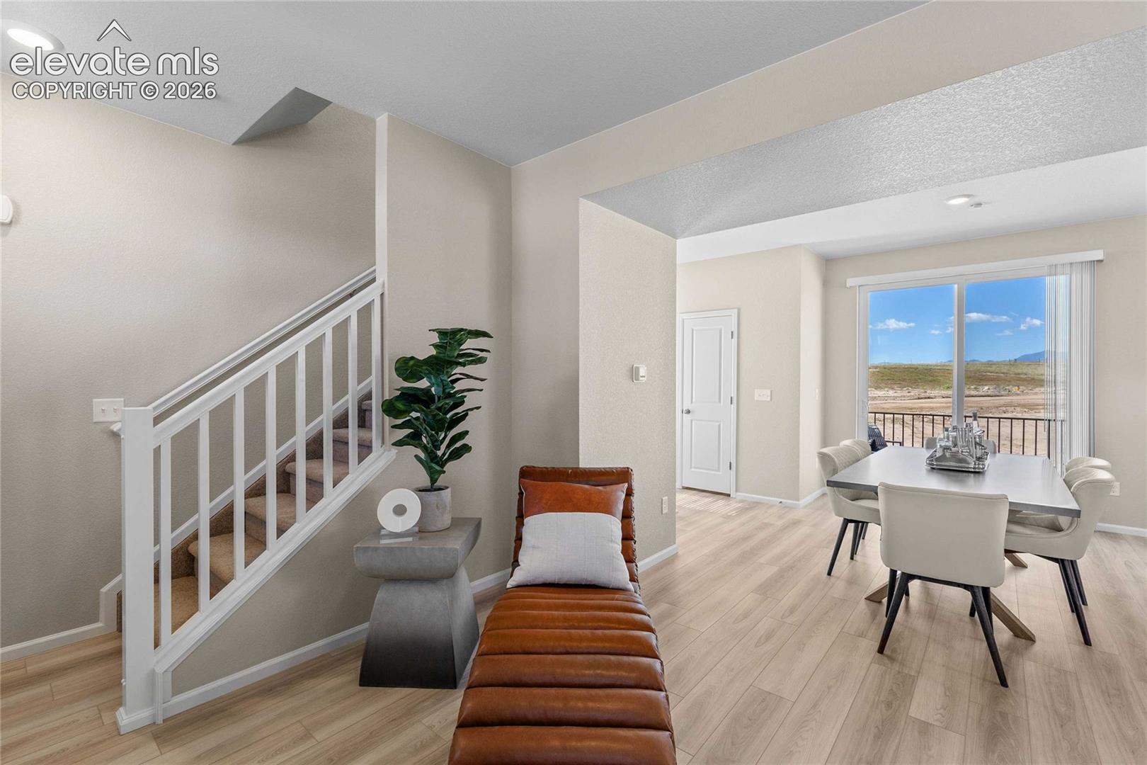 Light wood-finish flooring throughout, white painted staircase with carpeted treads, recessed lighting, and expansive window with outdoor scenery
*photos of a model home*