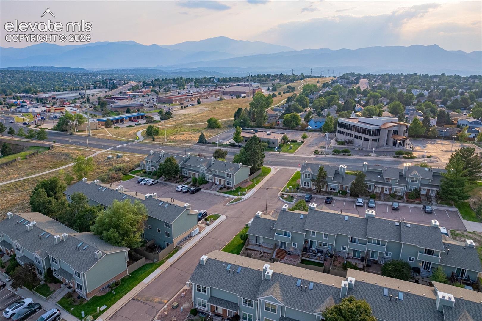 Residential community with a mountain backdrop, multiple asphalt parking areas, and mature trees throughout