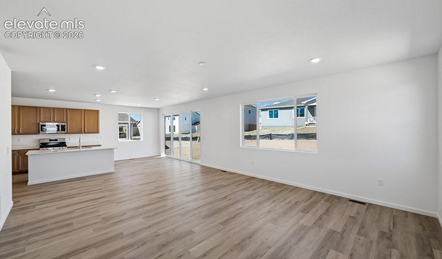 Open-concept interior featuring wood-finish flooring, recessed lighting, and a kitchen equipped with cabinetry, a peninsula, and built-in appliances