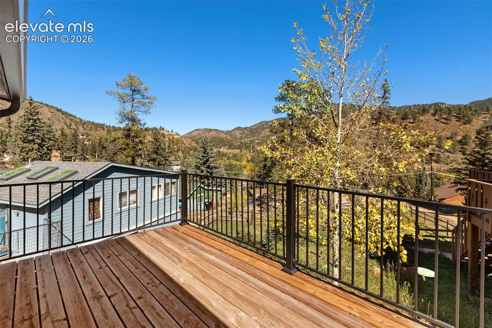 Elevated wood deck featuring black metal railings and a mountainous landscape backdrop