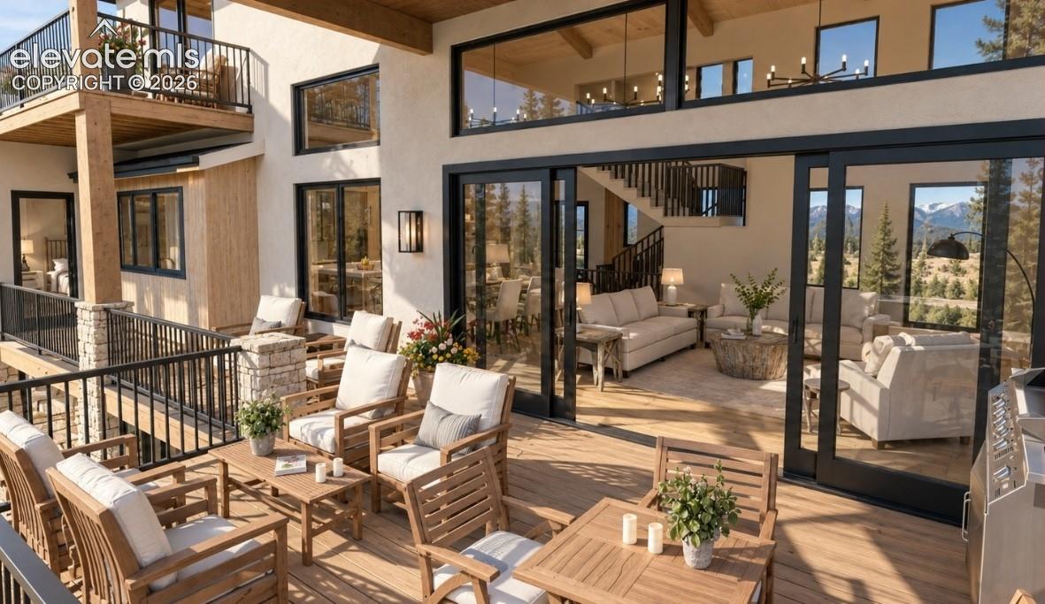 Expansive outdoor deck with a lower-level balcony, stone pillar accents, and a black railing system