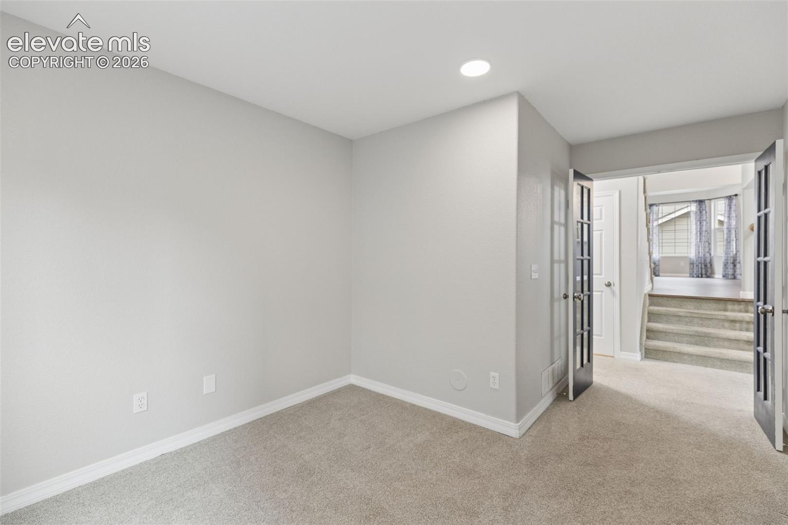 Neutral-toned interior space featuring recessed lighting, plush wall-to-wall carpeting, and double French doors with glass panes