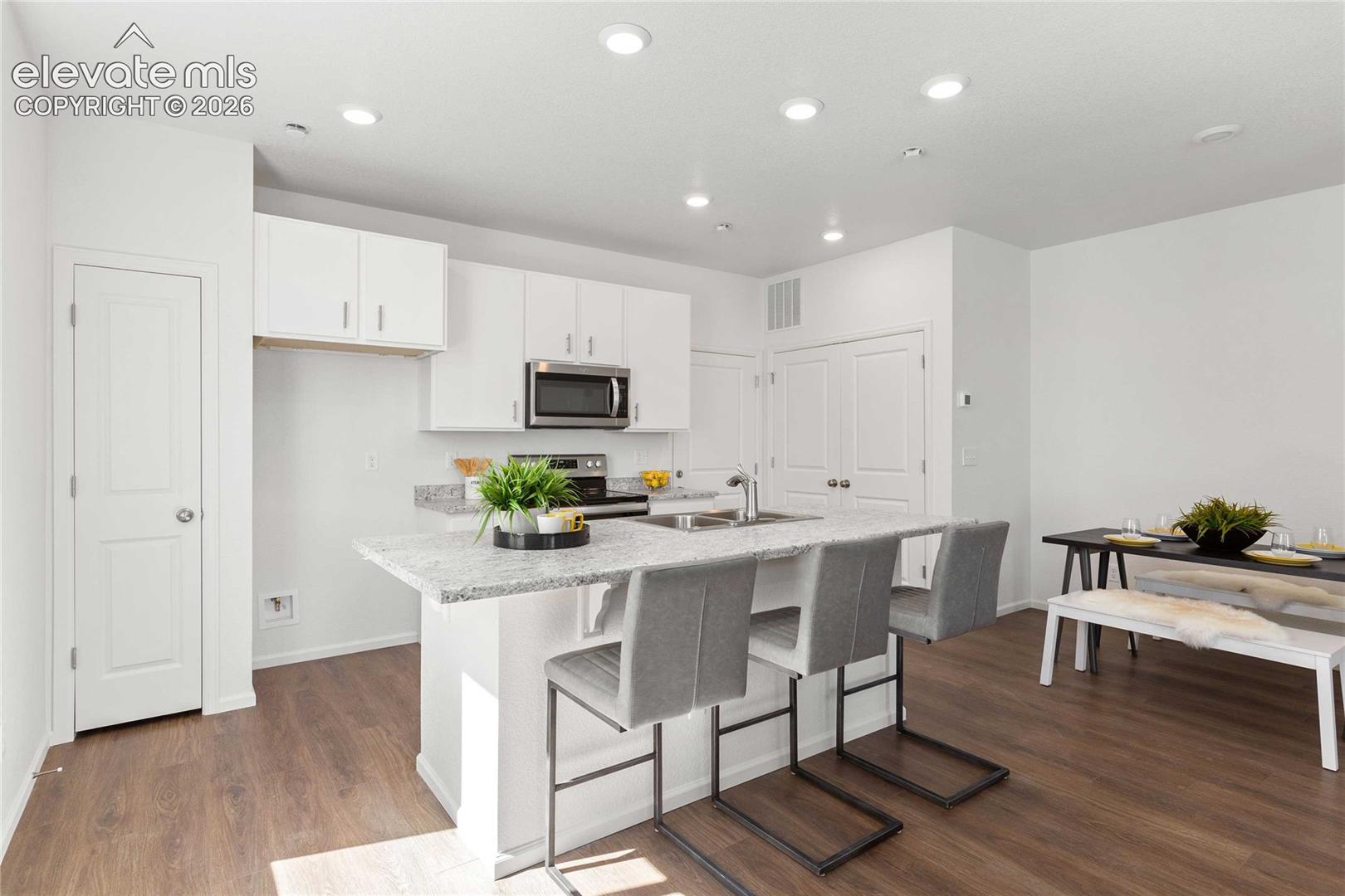 Kitchen featuring white cabinetry, stainless steel microwave, and a center island with a light-colored countertop
*photos  of a model home*