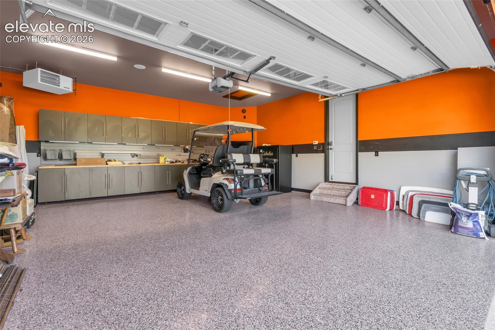 Finished garage featuring epoxy flooring, extensive wall-mounted cabinetry, integrated LED lighting, and direct-entry door with stairs