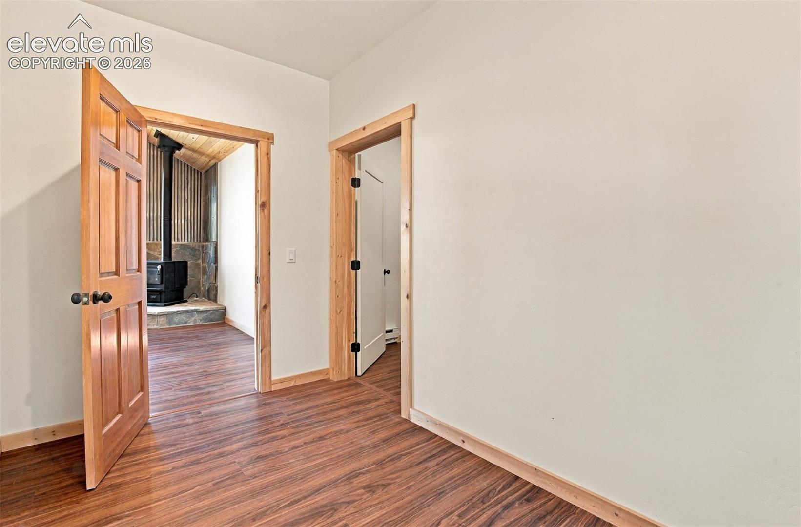 Interior space featuring wood-finish flooring, natural wood door and window casing, six-panel solid wood doors, and matte black hardware