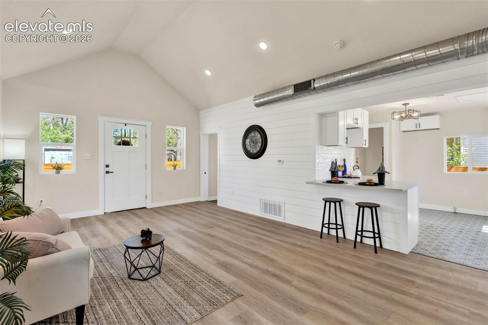 Open-concept living area with vaulted ceilings and recessed lighting
