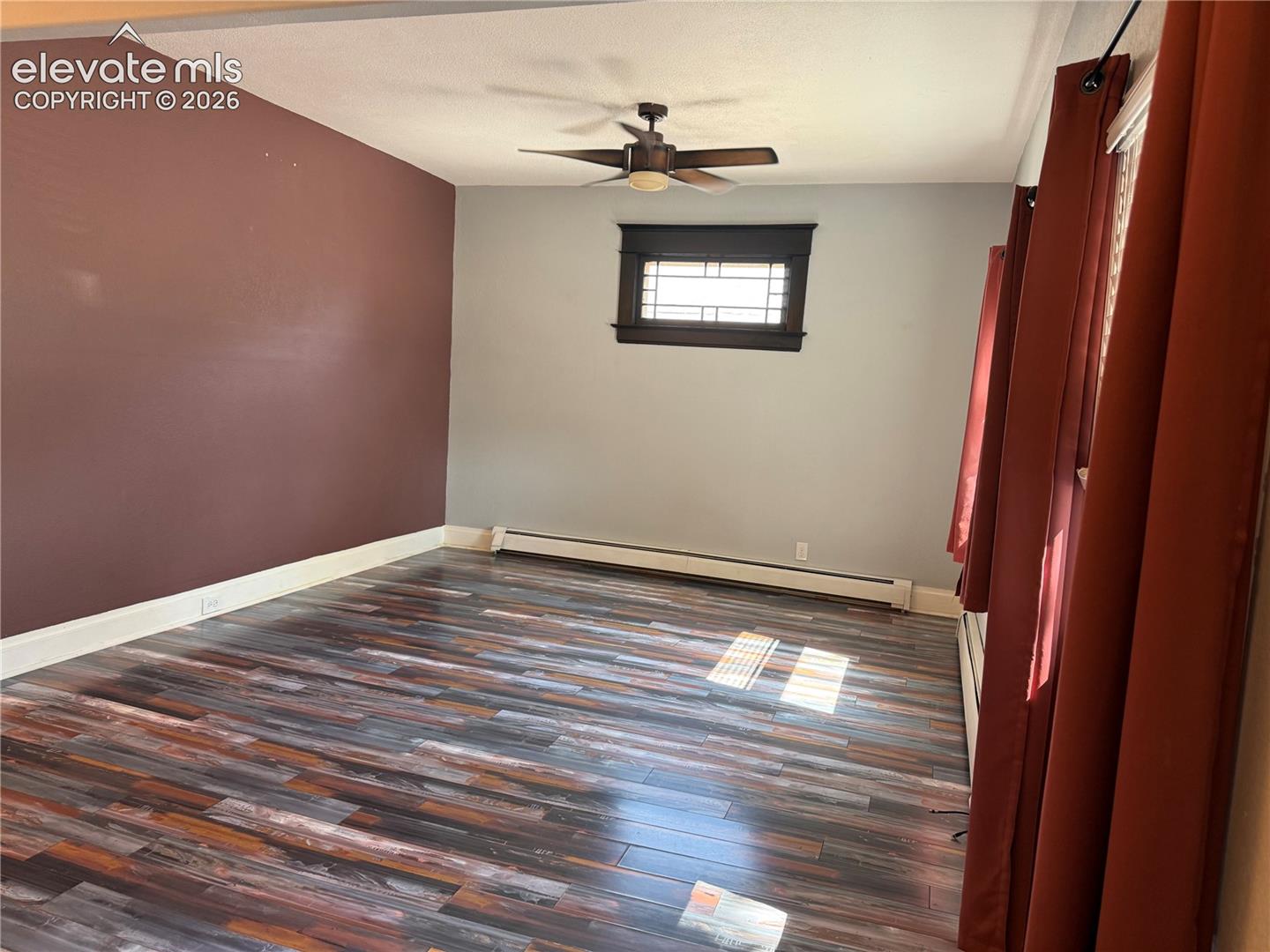 Wood-finish flooring, multi-pane window with dark trim, and a ceiling fan with integrated lighting