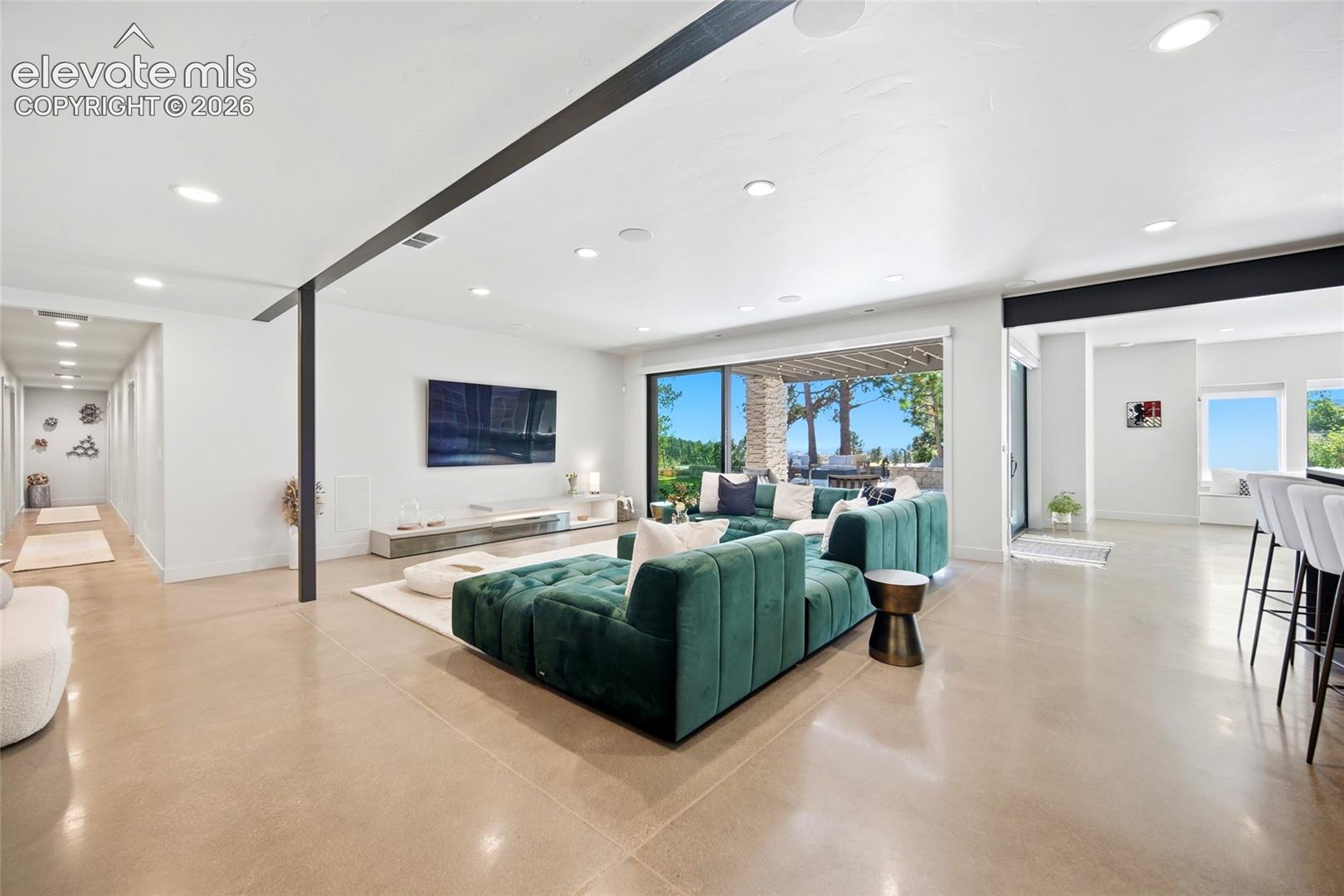 Polished concrete flooring, recessed lighting, and a sliding glass door opening to an outdoor patio
