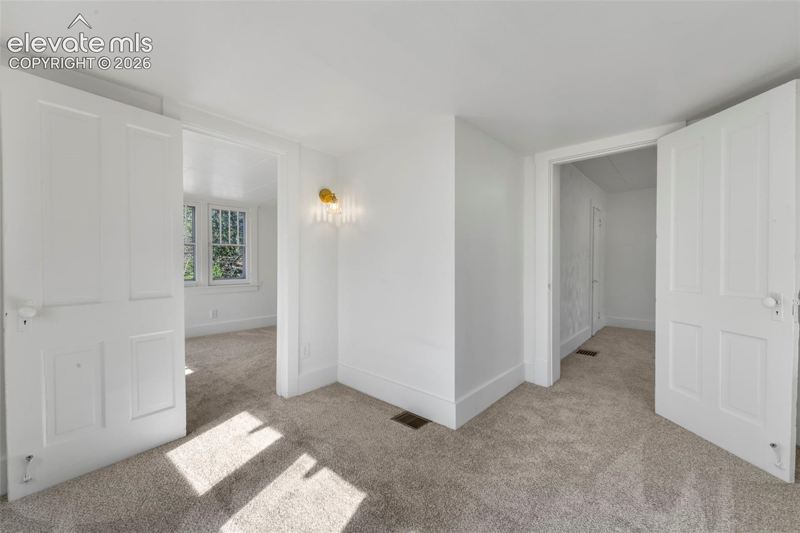 Neutral wall palette, plush wall-to-wall carpeting, four-panel interior doors, and decorative wall-mounted lighting