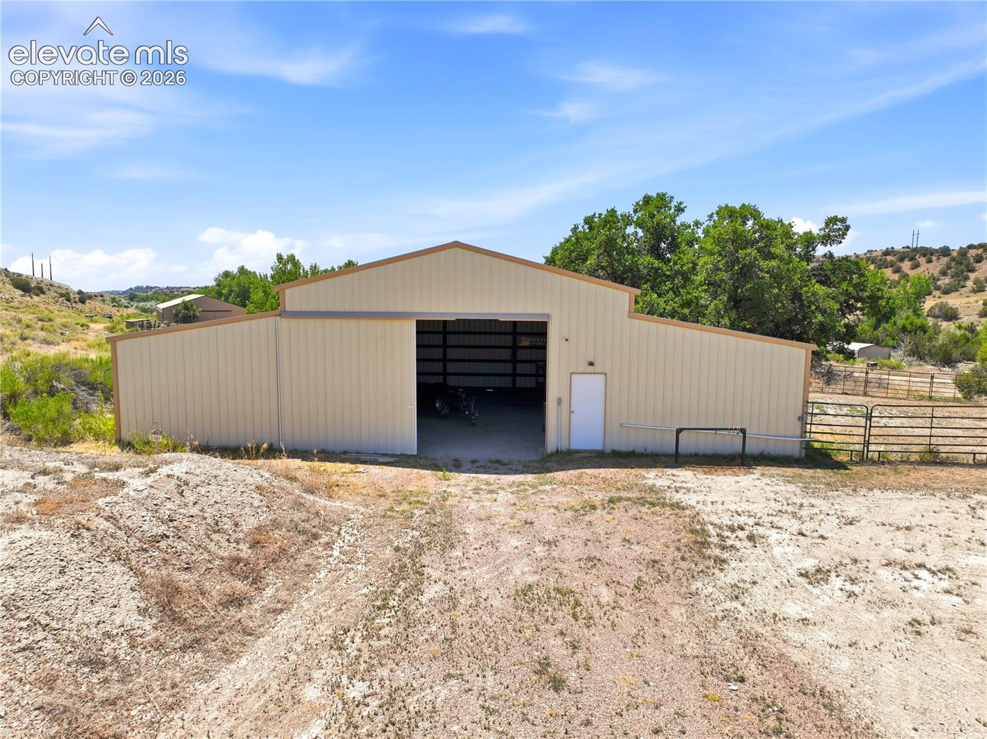 Metal-sided barn structure with a large sliding door, a single white entry door, and a peaked roofline