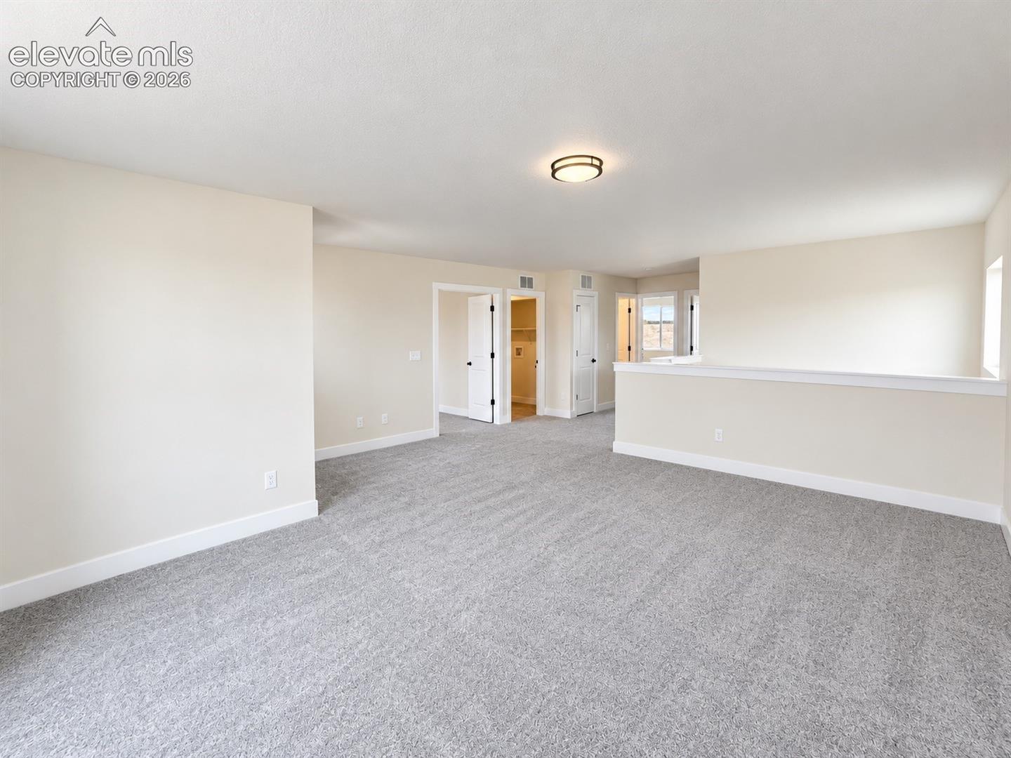 Spacious area featuring wall-to-wall carpeting, neutral interior paint, and a low-profile flush-mount ceiling light fixture