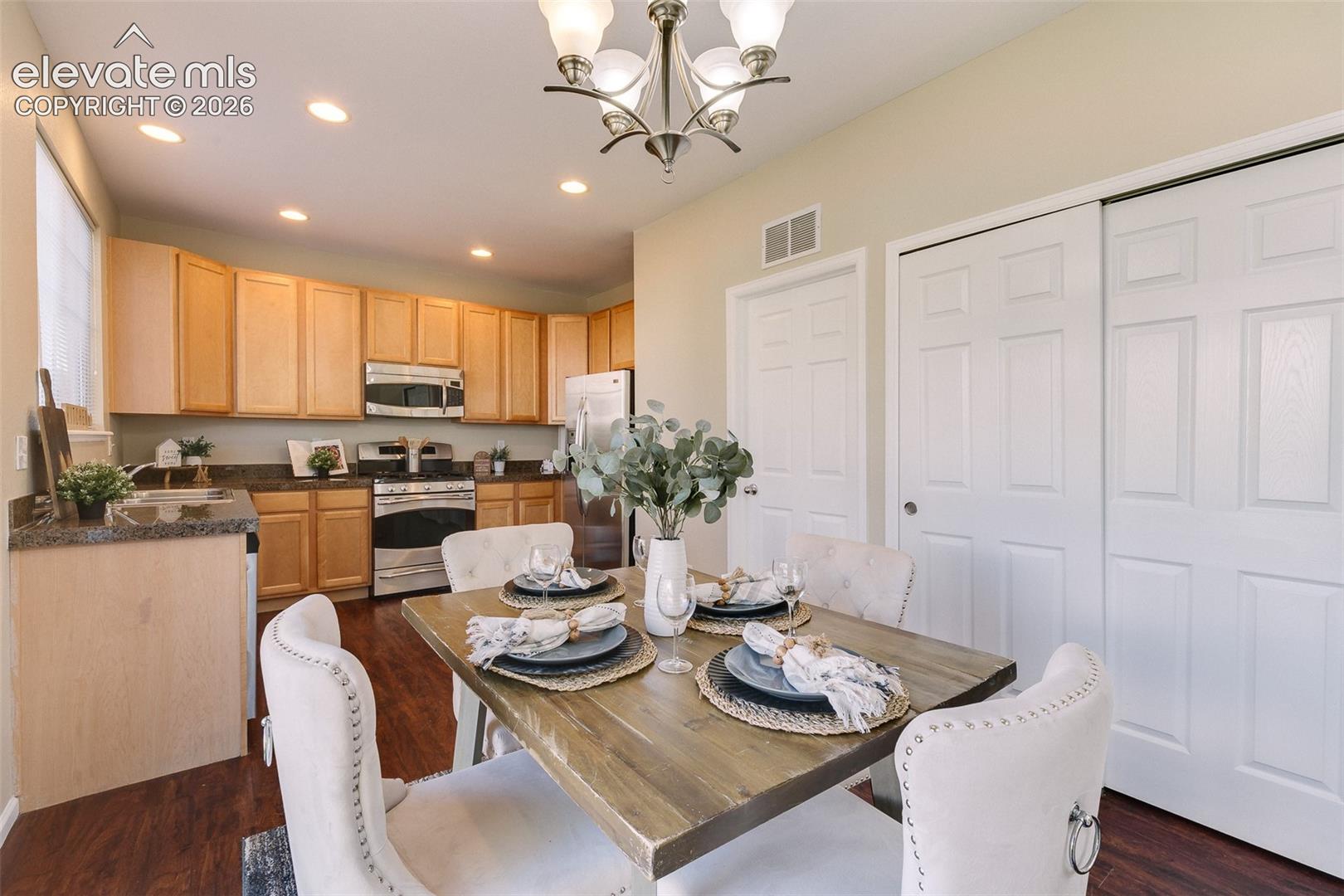 Kitchen featuring wood-finish cabinetry, stone-texture countertops, stainless steel appliances, wood-finish flooring, and recessed ceiling lighting