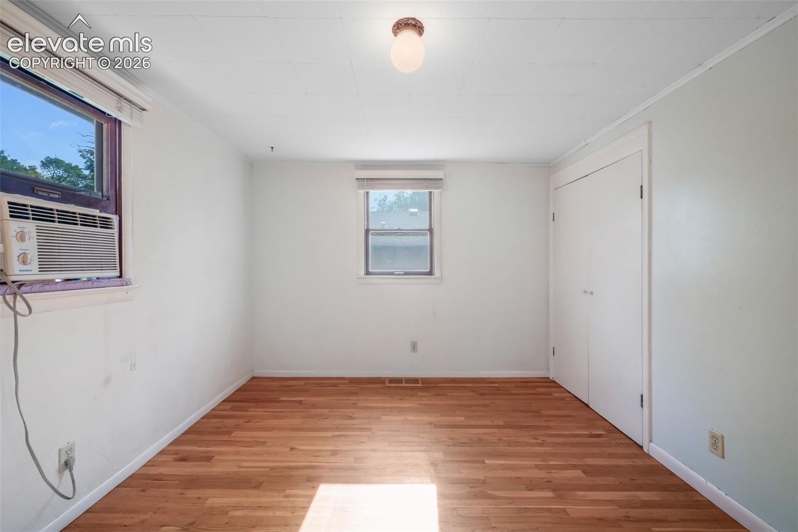 Wood-finish flooring with white walls and a ceiling-mounted light fixture