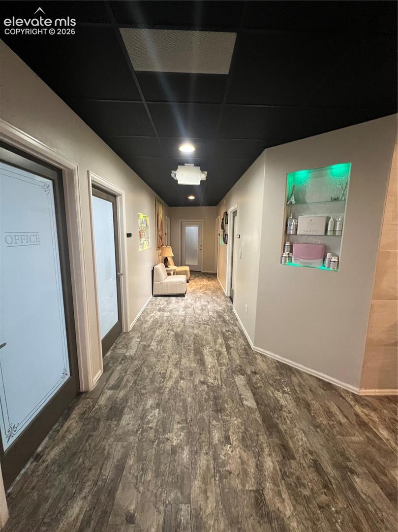 Hallway featuring wood-finish flooring, a bold matte black ceiling, recessed lighting, and a built-in recessed display niche with integrated accent lighting