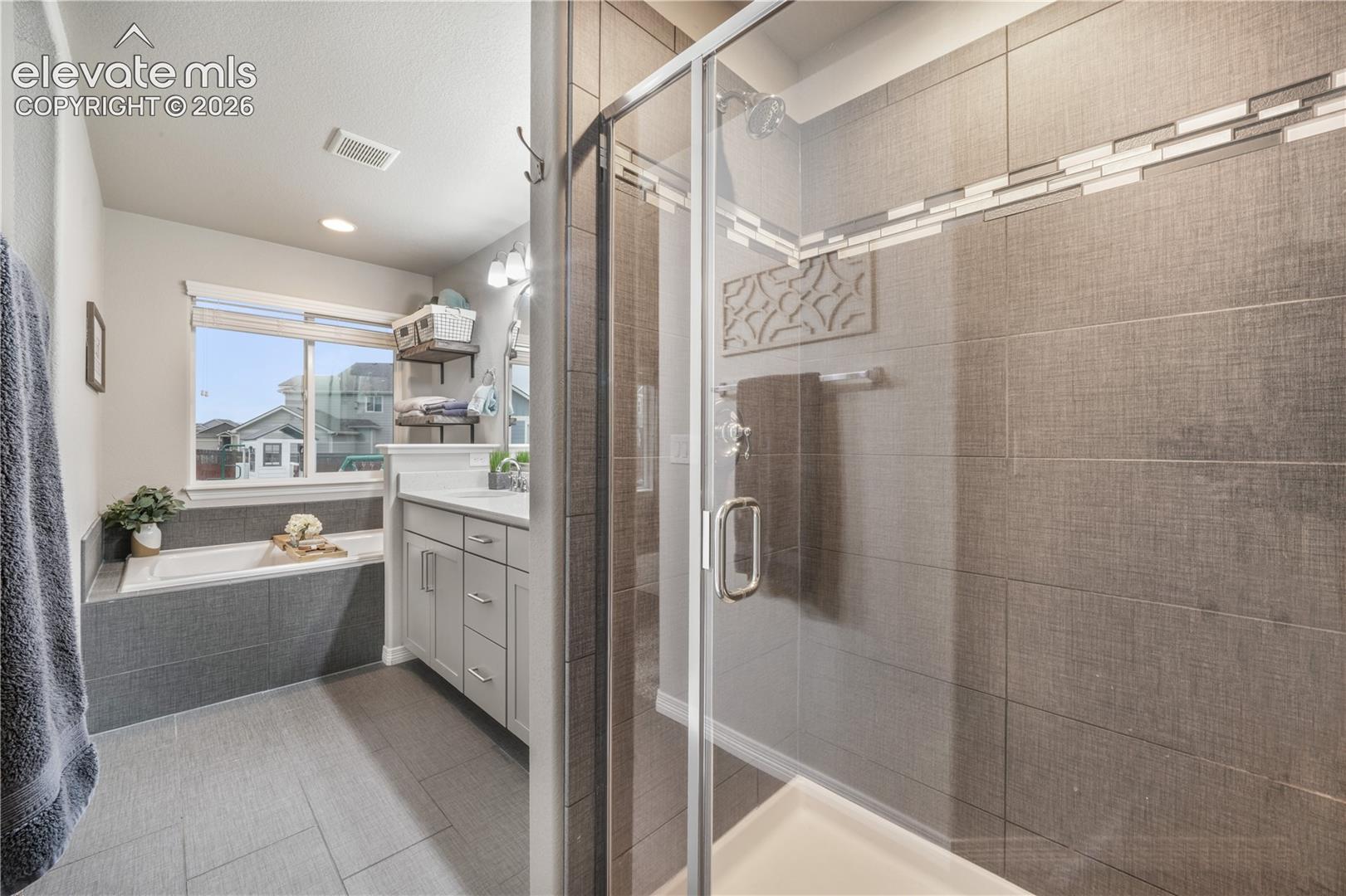 Glass-enclosed shower with tiled walls and a decorative accent band