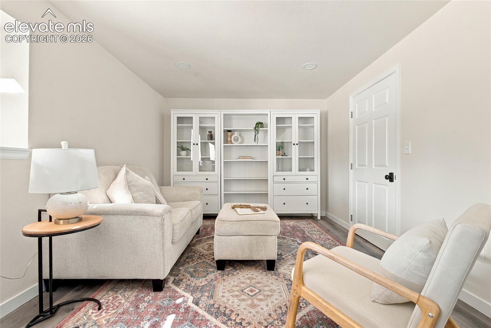 Basement second living area with recessed lighting, wood-finish flooring, built-in shelving, and a six-panel door