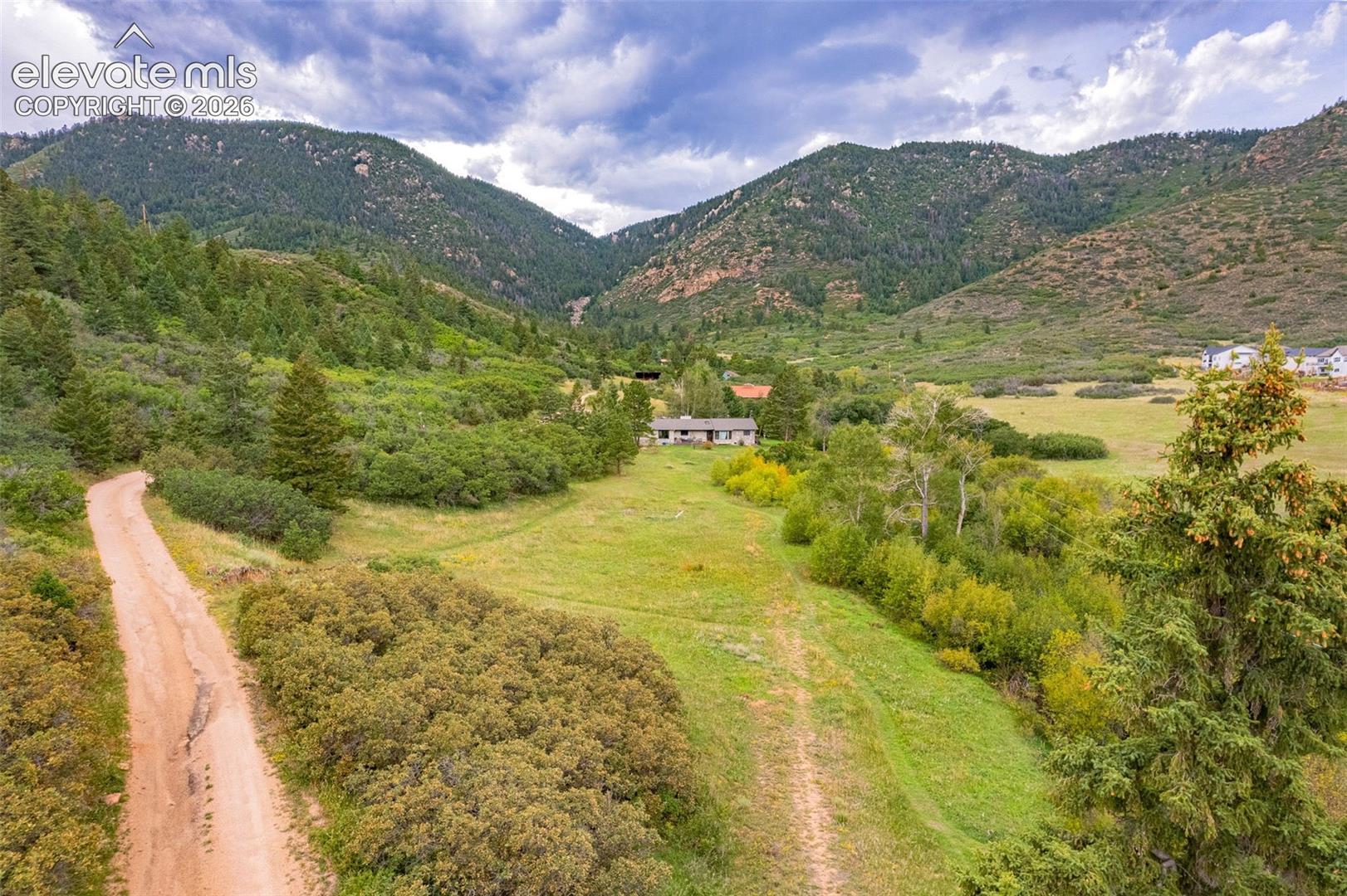 Mountain backdrop with extensive green landscape and a visible residence