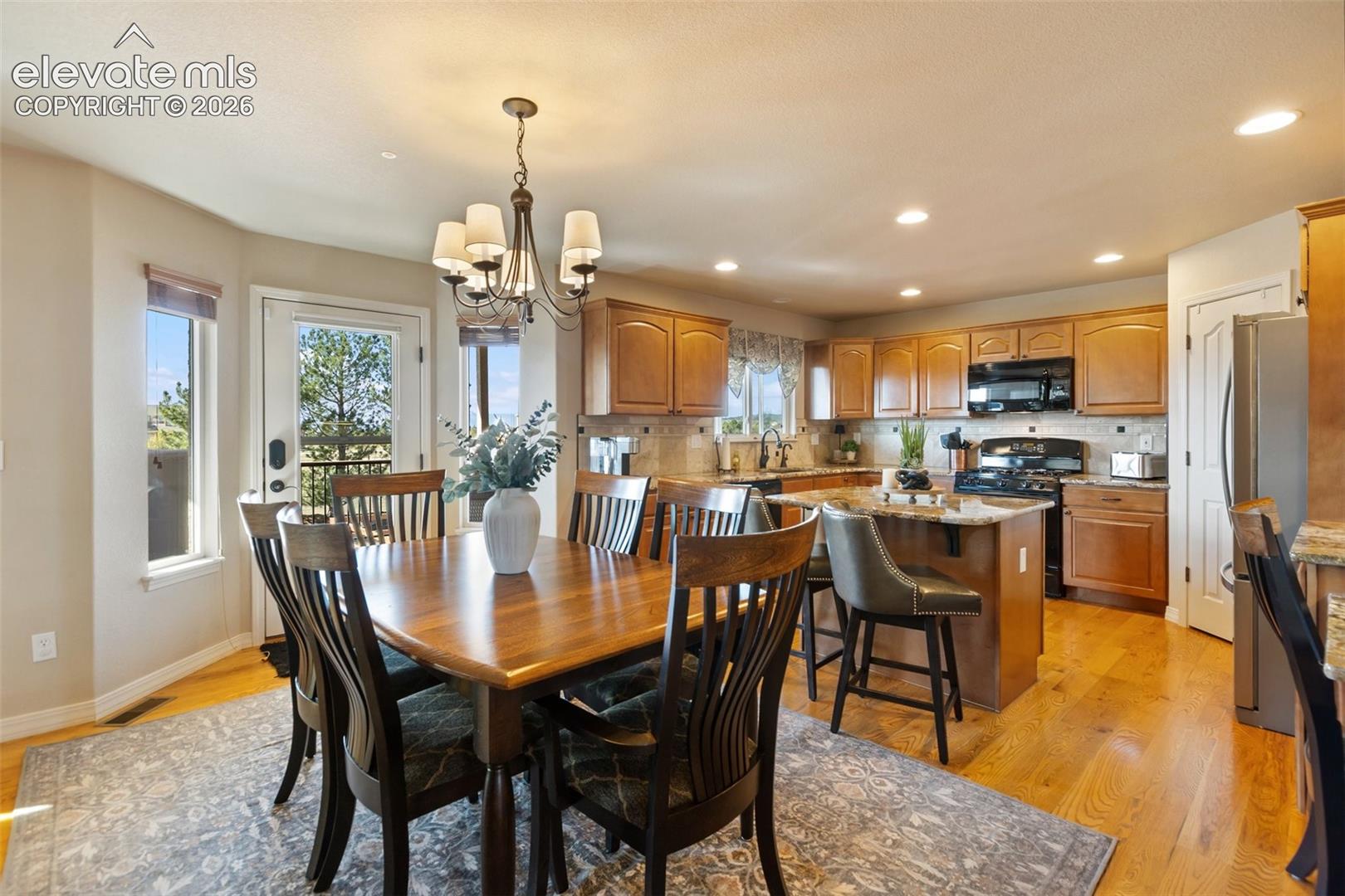 Kitchen featuring wood-finish cabinetry, natural stone countertops, a central island with bar seating, and hardwood flooring