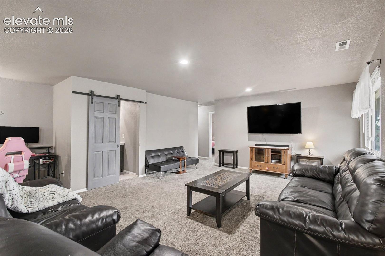 Cozy and inviting living room conveniently located next to the bathroom, featuring a stylish barn door for the bathroom entry and a warm, welcoming ambiance.