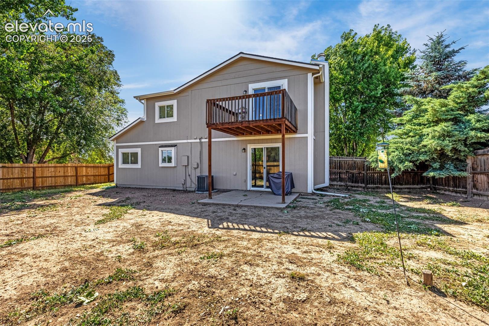 Exterior featuring horizontal siding, a second-story wooden deck, a concrete ground-level patio, and wood-panel perimeter fencing