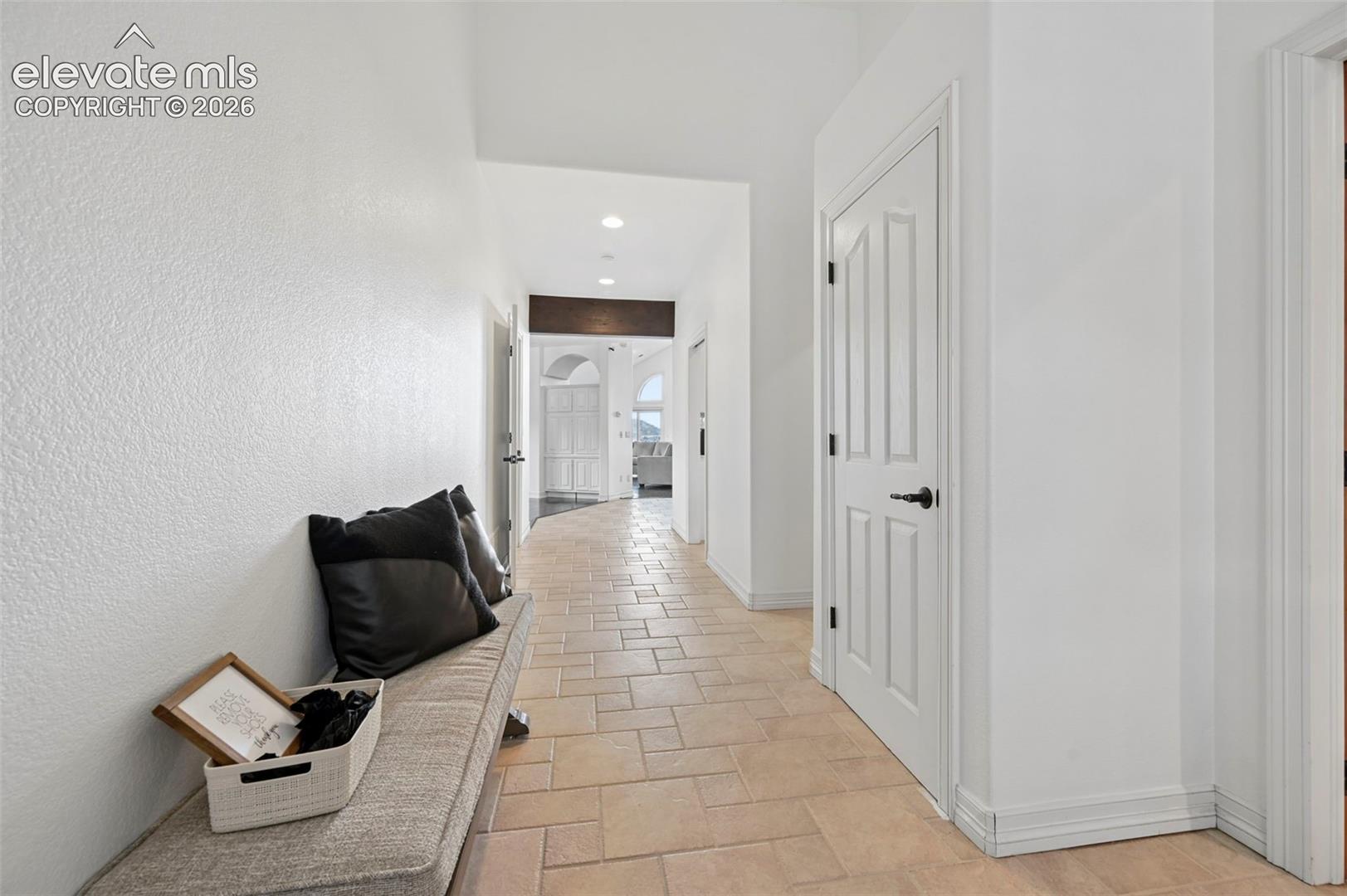 Hallway featuring light-toned tile flooring, recessed lighting, and white paneled doors with black hardware