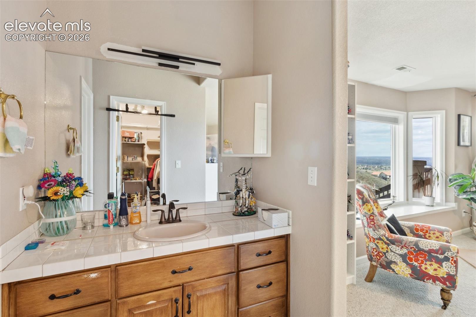 Bathroom vanity with a tile countertop and an oval basin