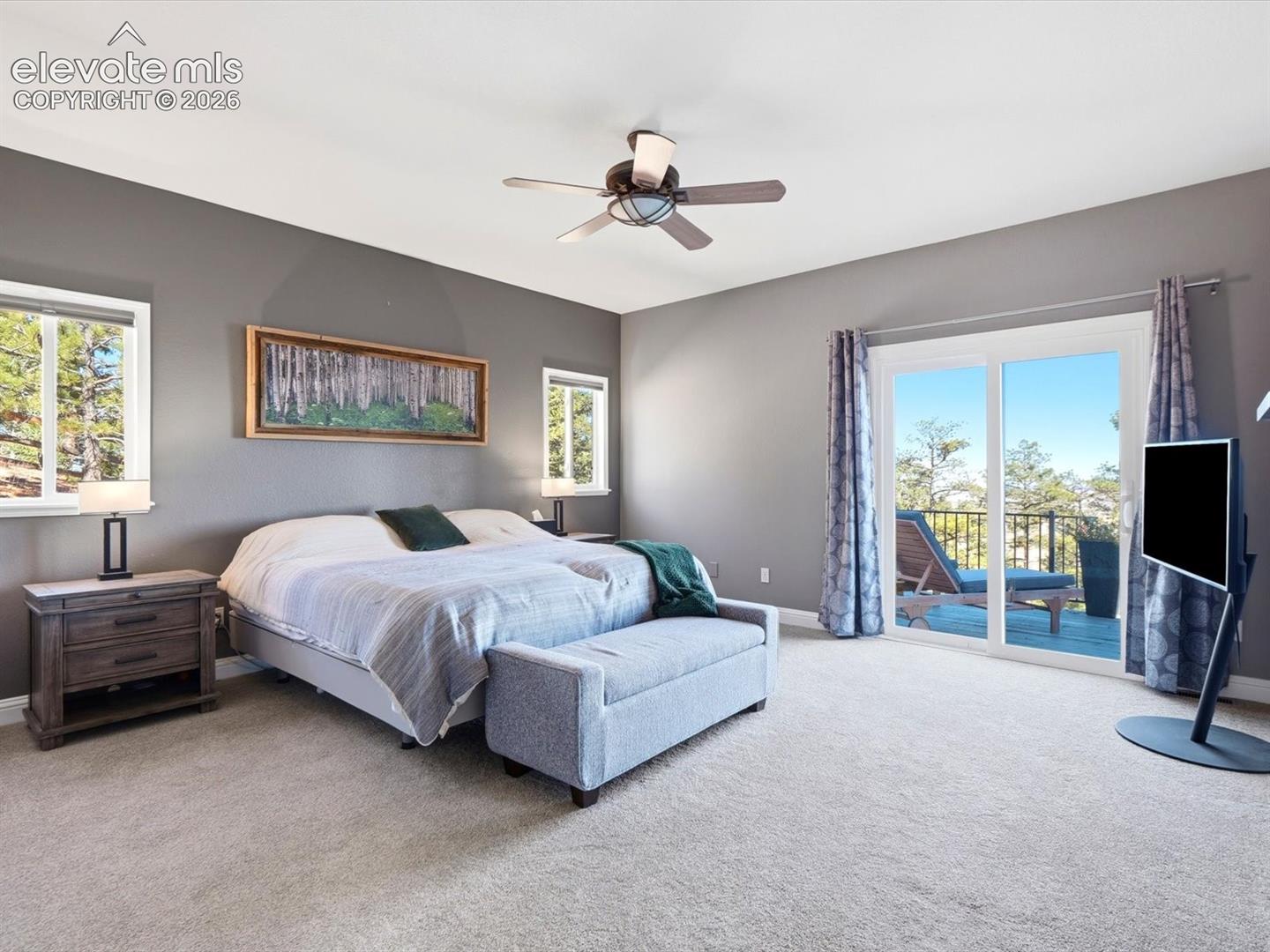Neutral-toned bedroom featuring carpeting, a multi-blade ceiling fan with integrated lighting, and sliding glass doors leading to a balcony