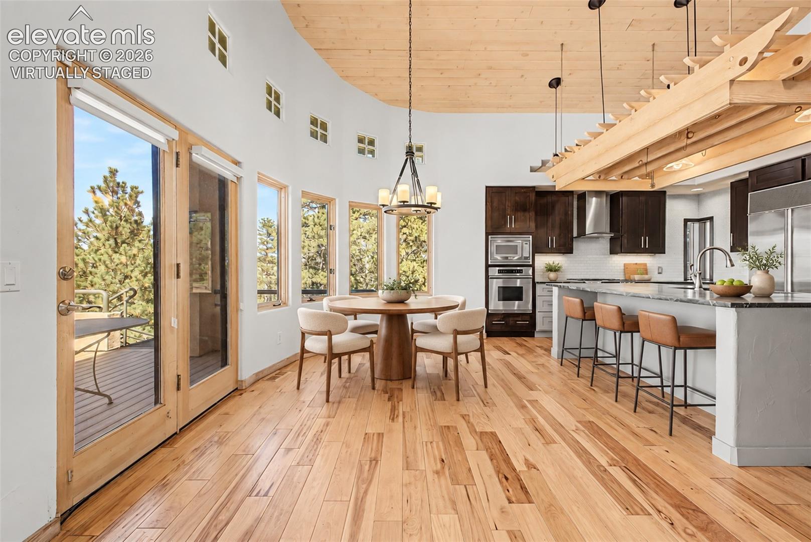 Virtually Staged
Open-concept living space with wood-finish flooring, a curved wall of windows, and a wood-paneled ceiling