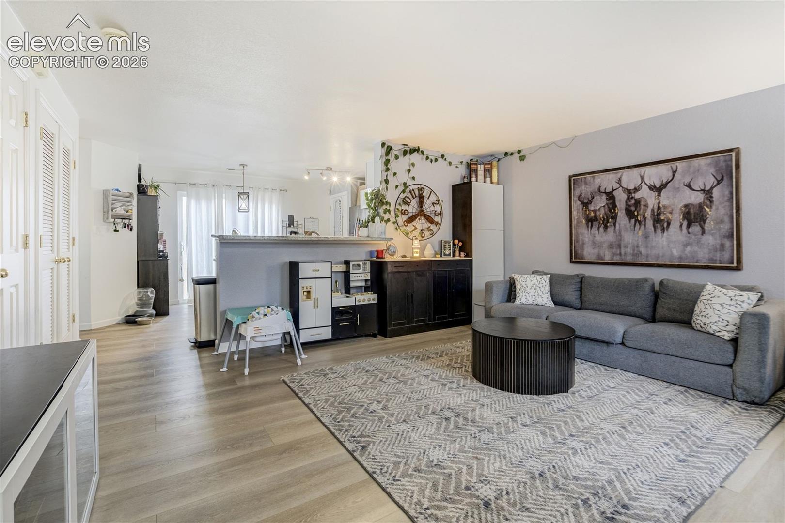 Open-concept living space with wood-finish flooring, a partial wall, white bi-fold closet doors, and recessed lighting