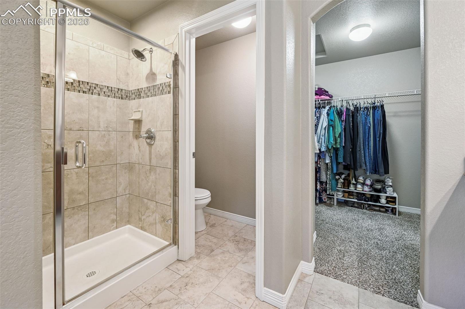 Full bathroom with light carpet, a walk in closet, and a shower stall