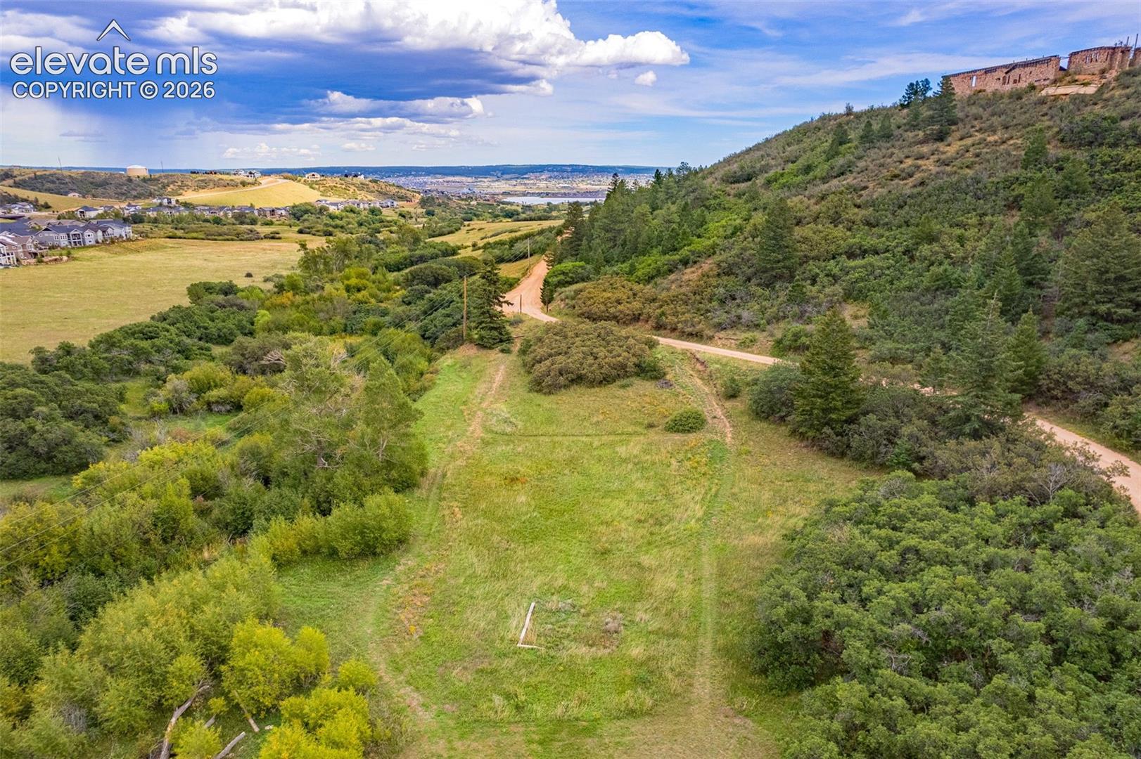 Expansive grassy terrain with surrounding dense foliage and a visible dirt path